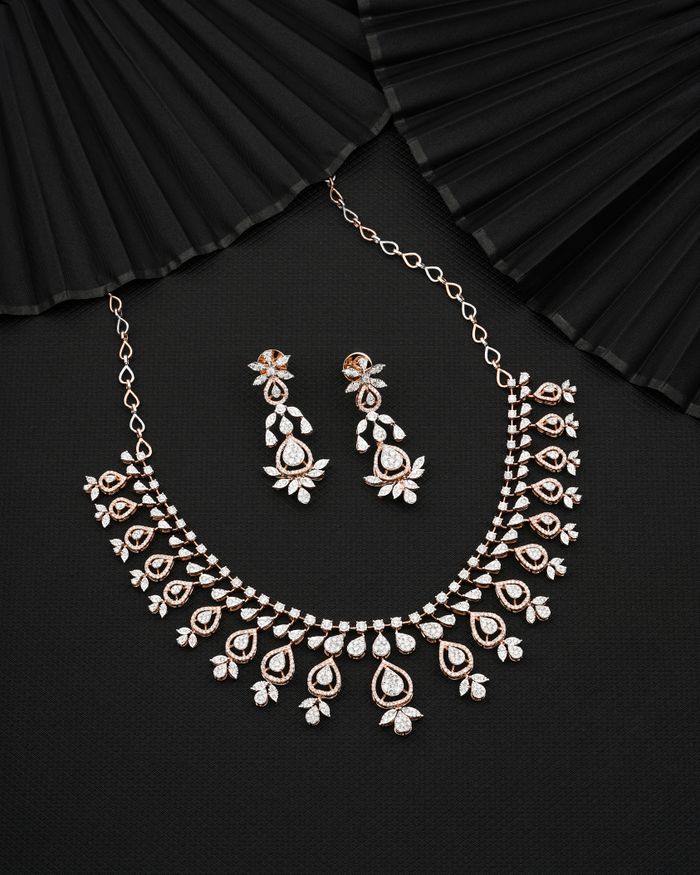 A beautiful diamond necklace and earrings set elegantly displayed on a dark fabric.